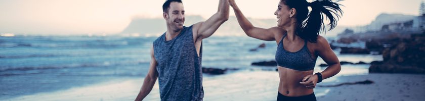 Fitness Couple giving each other high five after hard training session on the beach